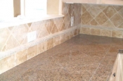 Granite tile countertops with travertine backsplash
